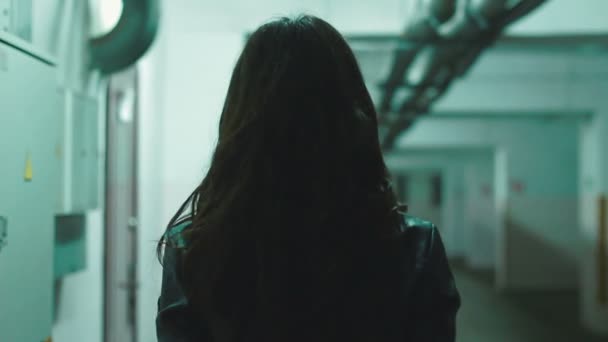 Камера следующая стилизованная в кожаной одежде девушка, идущая в старый гараж — стоковое видео
