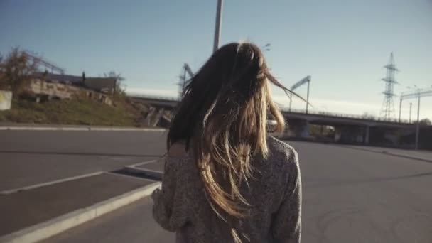 Blond meisje op hoge hakken lopen naar de auto op het asfalt op platteland achtergrond — Stockvideo