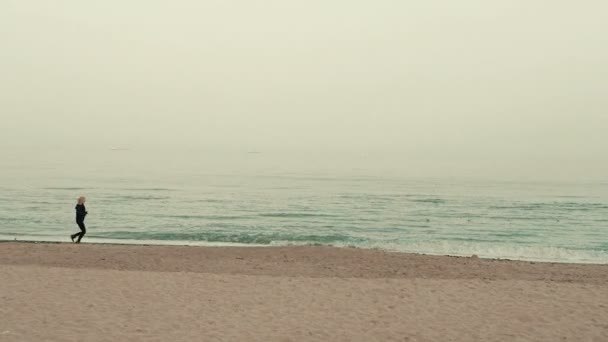 Mujer joven con una figura delgada corriendo en el mar al amanecer — Vídeo de stock