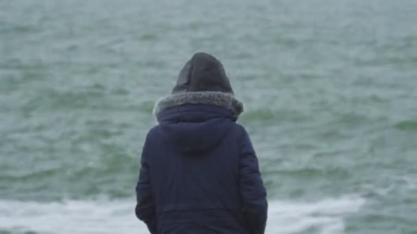 Giovane ragazza in cappuccio saltare dalla spiaggia sorridendo e ridendo della fotocamera — Video Stock