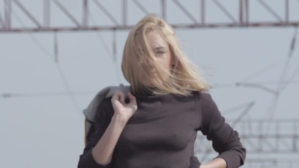 Mladý stydlivej model chůzi na železnici a usmívá se, zatímco vítr — Stock video
