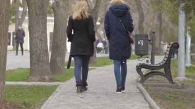 İki kız şehir parkı ile soğuk baharda yürümek.