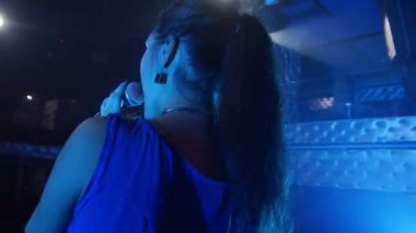 Gece kulübünde bir mikrofona çekici genç kadın şarkı söylüyor