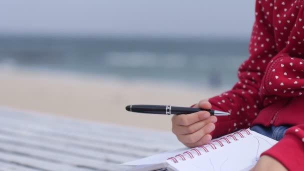 Little girls hands writing in the notebook near the sea — Stock Video