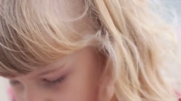 Niña escribiendo en el cuaderno cerca del mar a veces mira hacia arriba sus ojos — Vídeos de Stock