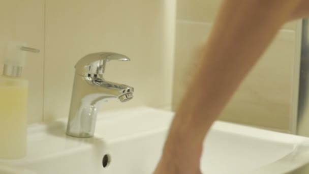 Mann in seinen Zwanzigern wäscht sein Gesicht an einem Waschbecken — Stockvideo