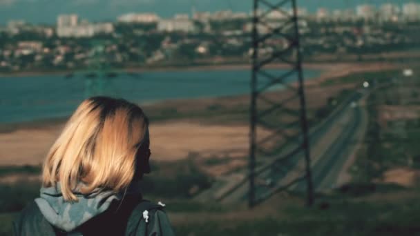 Ragazza vedi piloni della vecchia elettricità, lago con edifici sullo sfondo — Video Stock