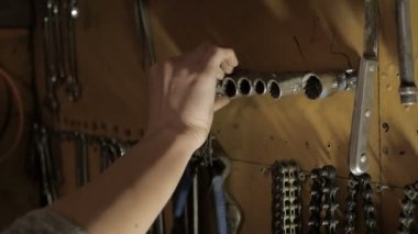 El bir İngiliz anahtarı alır ve geri asmak