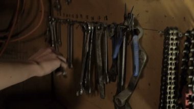 El bir İngiliz anahtarı alır ve geri asmak