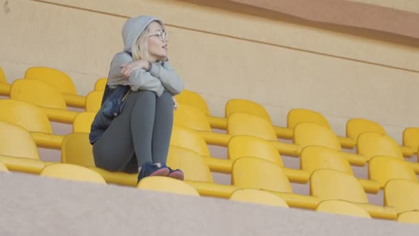 Дівчина сидить на стадіоні і радий дивитися, як його команда забила гол — стокове відео