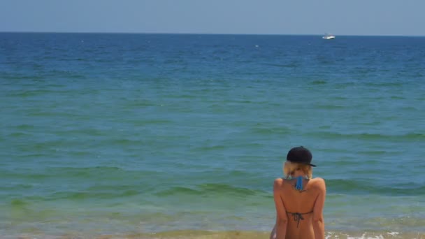 Pihentető a strandon és a katamarán hajó a tengeren a háttérben a pillantást a lány — Stock videók