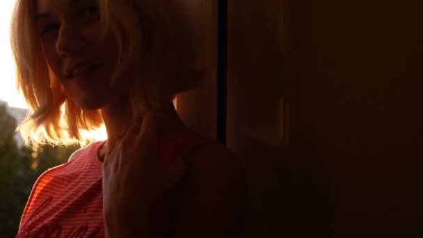 Blondes Mädchen blickt lächelnd in die Kamera, als ein Sonnenstrahl durch den Sonnenuntergang bricht — Stockvideo