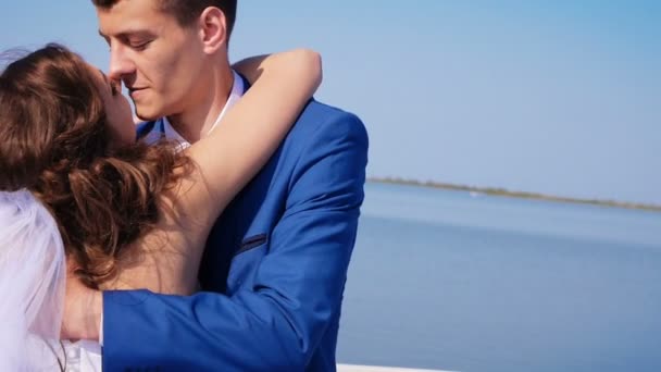 Jonggehuwden kus en glimlach op een zeilen jacht slow motion in de zee — Stockvideo