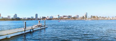 Long Beach ufuk çizgisinin panoramik manzarası ve Güney Kaliforniya limanı. Deniz manzaralı güneşli bir şehir manzarası ve Los Angeles yakınlarındaki ünlü bir seyahat merkezi olan Queensway Körfezi 'nde bir rıhtım.