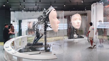 Las Vegas, Nevada, ABD - 09.06.2025: Geleceği parlak bir perakende mağazasından lüks güneş gözlüğü satın alan müşteriler, camların içinde dev animatronik robot kafaların bir kinetik sanat kurulumu olarak yer aldığı