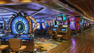 Las Vegas, Nevada, ABD - 09.07.2025: Lüks bir kumarhane zemininin iç görünümü sıralı modern slot makineleri ve renkli neon ışıklandırmalı önemli bir Big Wheel oyunu