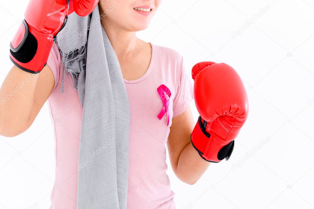 Asian women put a pink ribbon on their tops. And wearing boxing gloves on a colored background Breast cancer concept, cancer prevention concept.