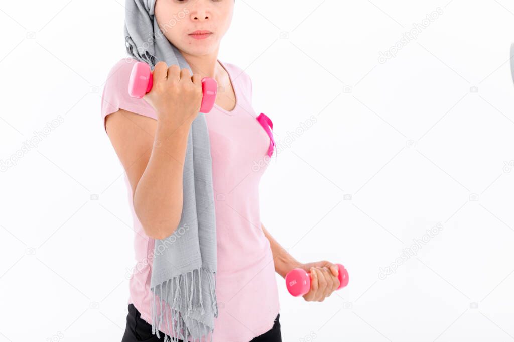 Asian women muslim religious women in hijab attach a pink ribbon to their tops. Doing exercise by lifting pink dumbbells.  breast cancer concept, cancer prevention concept. Acne and dark spots.
