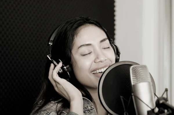 Asian female singer singing in a recording studio. Female singer singing and playing guitar.