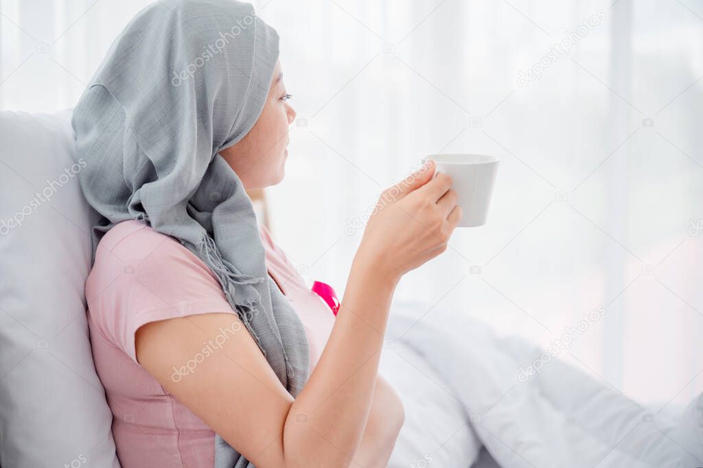 Recreation and People Concept - Young women enjoy a cup of coffee or tea on the bed at home bedroom.