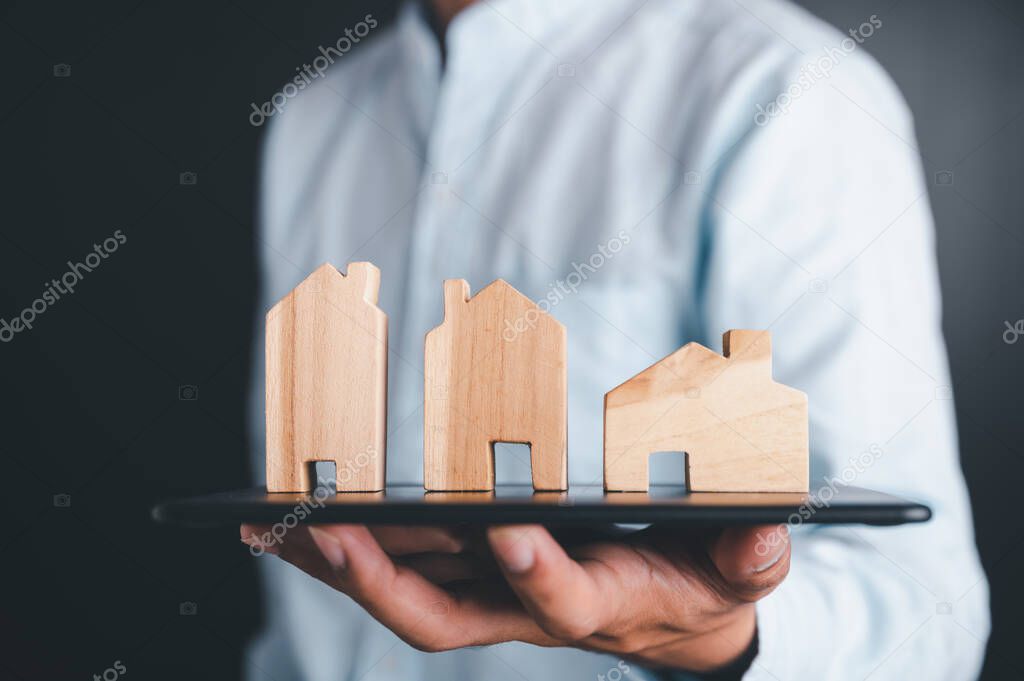 Real estate agent holds a house key to exchange with his client after signing a home purchase contract, idea for real estate, moving or renting a property.