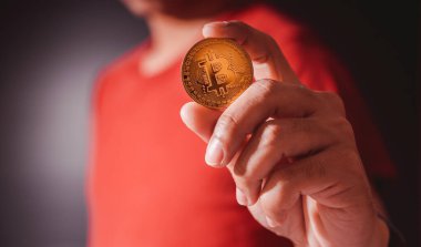 Yüzen altın Bitcoin işadamının elinde. Siyah arka planda sanal para. Bitcoin ile para kazan, engelleme zinciri transferi.