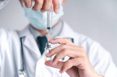 Doktor ya da bilim adamı COVID-19, aşı ve laboratuvar deneylerine karşı bir şırınga ve aşı taşıyor. COVID-19 virüsüne karşı koruma kavramı.