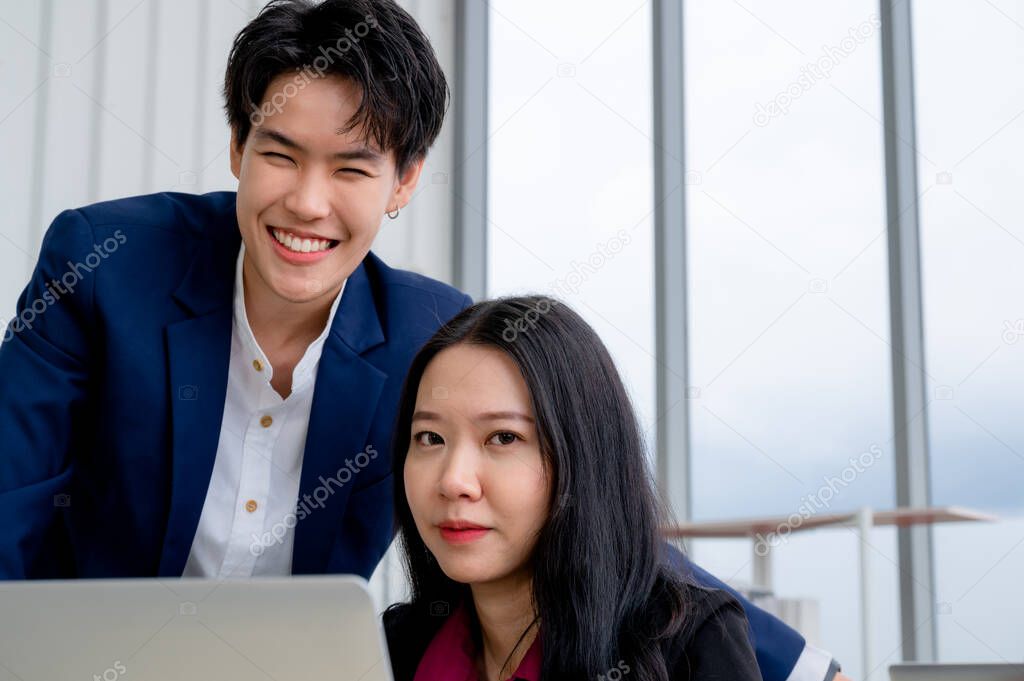 Confident and smart beautiful businesswoman in formal attire stands in the office. With a group of friends and laptop in the background. A cheerful idea to work within the workspace.