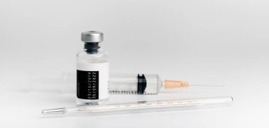 The vaccine vials, syringes and stethoscope are placed together on a white background. COVID-19 virus protection concept, vaccine invention and production concept.