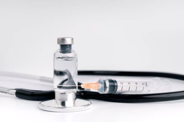 The vaccine vials, syringes and stethoscope are placed together on a white background. COVID-19 virus protection concept, vaccine invention and production concept.