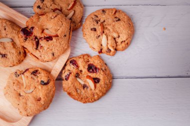 Piles of delicious chocolate chip cookies on a white plate with a milk bottle. Pastry utensils with white linen napkins on a wooden table. Delicious on a white plate with a bottle of milk.