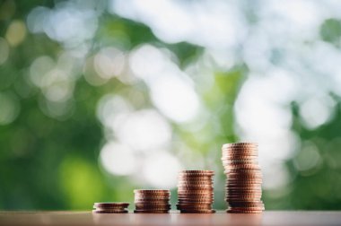 Sanal bir masa üzerine yerleştirilen madeni paralar, konsept ve iş stratejisinin doğal yeşil arka planlı büyümesi.