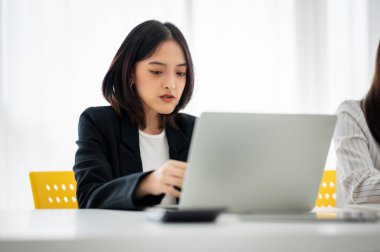Takım elbiseli Asyalı iş kadını konferans odasında dizüstü bilgisayar kullanıyor..