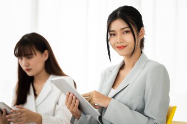 İş kadınları, toplantı odasında arkadaşlarıyla tablet ekranda gösterilen tablolar ve grafikler hakkında konuşurken gülümseyerek oturdular. Beyin fırtınası ve takım çalışması konsepti.