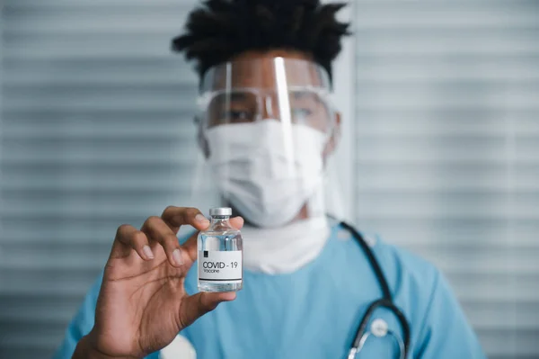 Médico Afroamericano Con Máscara Protector Facial Sosteniendo Una Jeringa Con —  Fotos de Stock