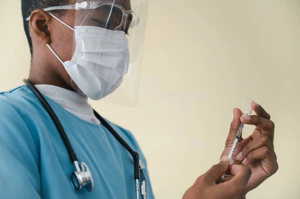 Médico Afroamericano Con Máscara Protector Facial Sosteniendo Una Jeringa Con —  Fotos de Stock