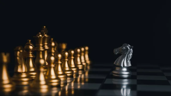 Uma peça de xadrez da rainha de ouro em pé com a vitória perto de uma peça  de xadrez da rainha de prata caída em um tabuleiro de xadrez em fundo  escuro.