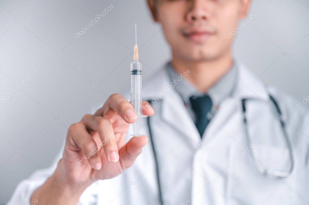 Doctor or scientist carries a syringe and a vaccine against COVID-19, vaccination and laboratory experiments. Concept of protection against the COVID-19 virus.