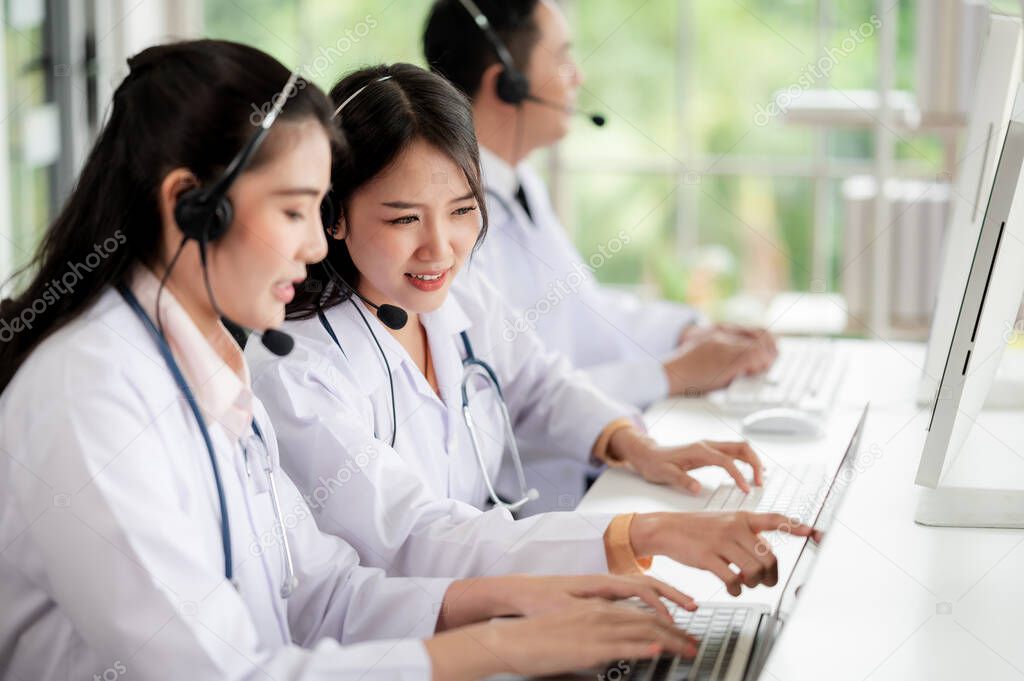 Asia medical service team health advice online. Smiling face stood wearing the headphones with a microphone and stethoscope in clinics.Concept of remote medicine, health care call center online.