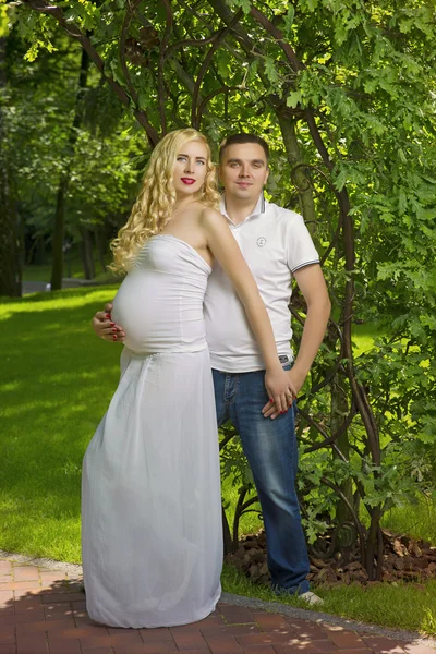 Felice e giovane coppia incinta in parco in estate — Foto Stock