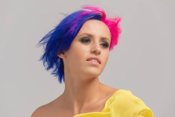 Портрет жінки з яскравим кольоровим волоссям, синьо-рожевою зачіскою. дівчина з коротким волоссям, одягнена в жовту сукню з відкритими плечима — стокове фото