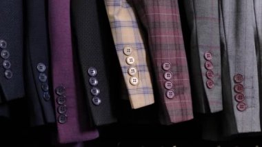 Alışveriş merkezindeki giyim mağazasında erkek giyim kuşamaları farklı takımda. Düğmeli bir sıra ceket kolunun görüntüsü.