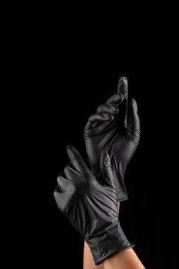 Siyah arka planda takılan siyah lastik eldivenler. virüs koruması