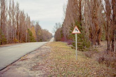 Şehir yolu ormana girince uyarı işareti. Yol işareti sonbahar renklerinde. Yasak bölgede Çernobil Yolu. Pripyat şehrindeki radyoaktif bölge, terk edilmiş hayalet şehir. Ukrayna