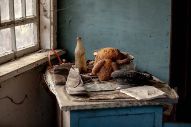 Oyuncak ayı veya cheburashka, Ukrayna 'nın Çernobil Yasak Bölgesi, Çernobil şehrinde terk edilmiş Pripyat şehrindeki anaokulunda anaokulunda botlar ve kep masasında.