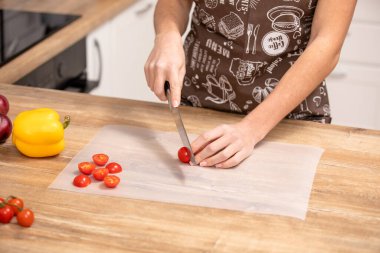 Domates doğrama. Kadın mutfakta vişneli domates kesiyor. Ev yemeği.