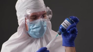 Doktor şırıngaya aşı yazıyor, şırıngada koronavirüs enfeksiyonu ilacı, bir tıp çalışanı, Coronavirus enfeksiyonundan COVI-19 için ilaç tutan bir doktor, yakın plan..