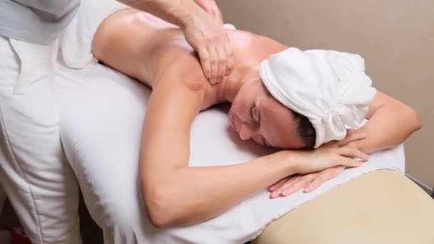 Чоловік-терапевт робить масаж для пацієнта, який лежить на дивані в спа-кабінеті. Жіночий клієнт отримує процедуру омолодження масажу спини в клініці краси. масаж плечей і шиї . — стокове відео