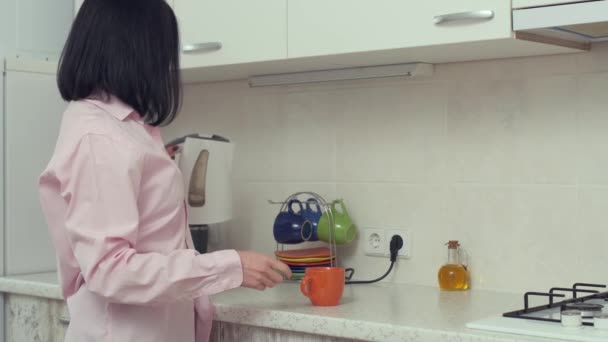 Femme au foyer verser de l'eau chaude dans la théière pour préparer le thé pour le petit déjeuner le matin. Cuisine moderne — Video