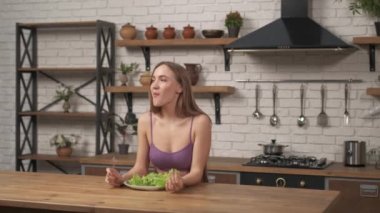 Ev mutfağındaki masada oturan bir kadın. Lahana yiyen sporcu kız diyete yapışır.